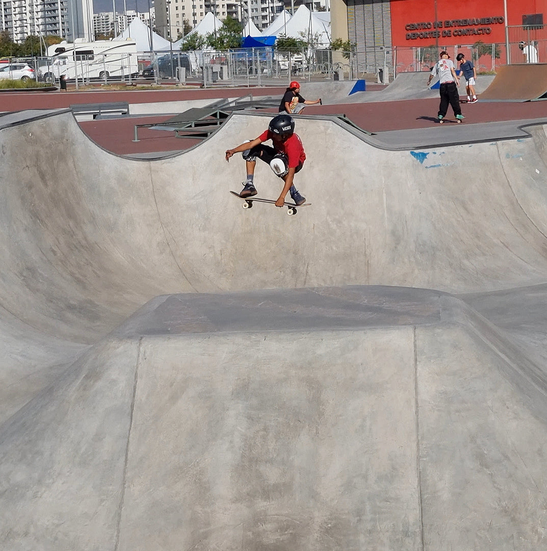 Salto en skate con tabla de skate igl en skate park con skaters