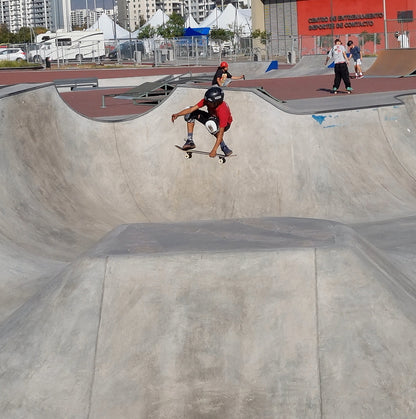Salto en skate con tabla de skate igl en skate park con skaters